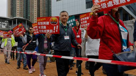 Protesters wearing numbered name tags march in Hong Kong under strict rules
