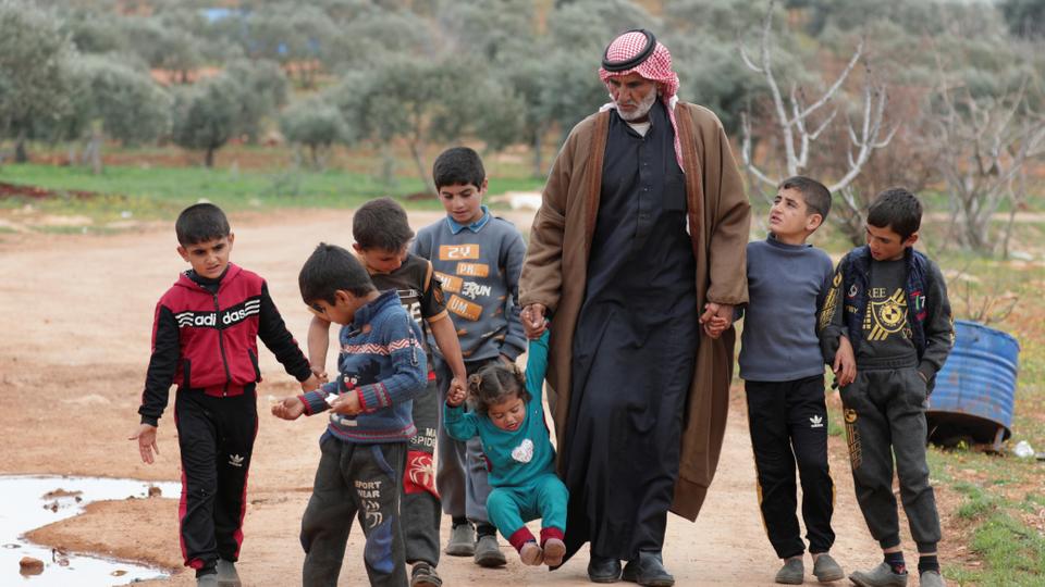 Syrian farmer, walks with his grandchildren, at an internally displaced camp in northern Idlib, Syria on March 11, 2021.