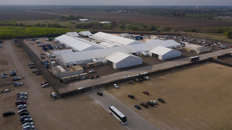 A tour bus exits a US Customs and Border Protection temporary processing center after dropping off migrants in Donna, Texas, US, March 15, 2021. Picture taken with a drone.