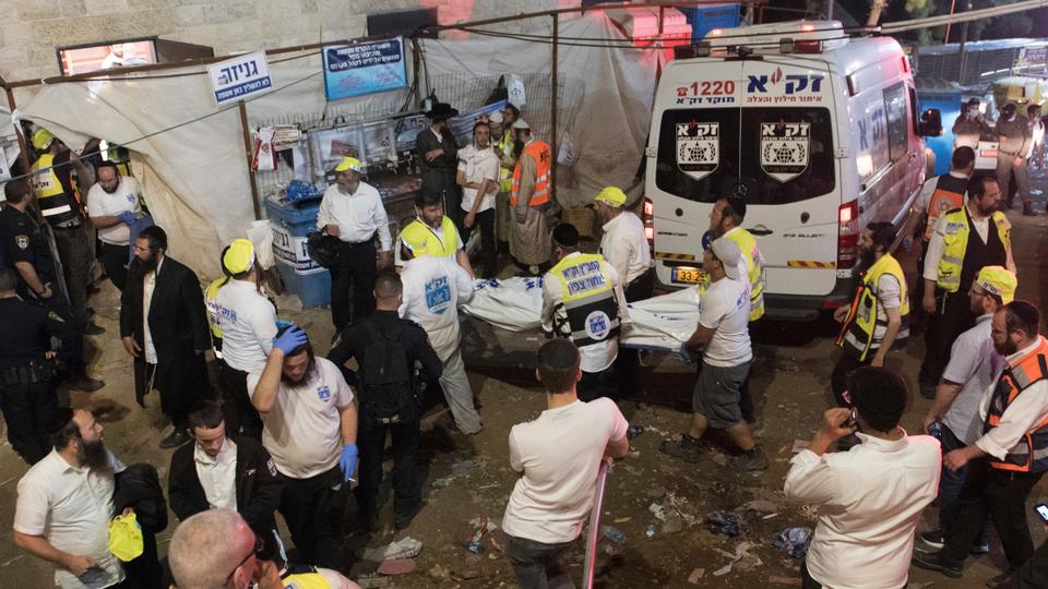 Israeli security officials and rescuers carry a body of a victim who died during a Lag Ba'Omer celebrations at Mt Meron in northern Israel, Friday, April 30, 2021.