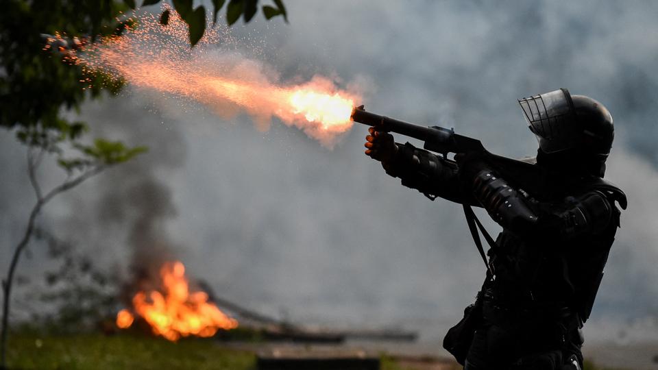 A riot police officer fires tear gas at demonstrators during clashes following a protest against a tax reform bill launched by President Ivan Duque, in Cali, Colombia, on 30 April 2021.