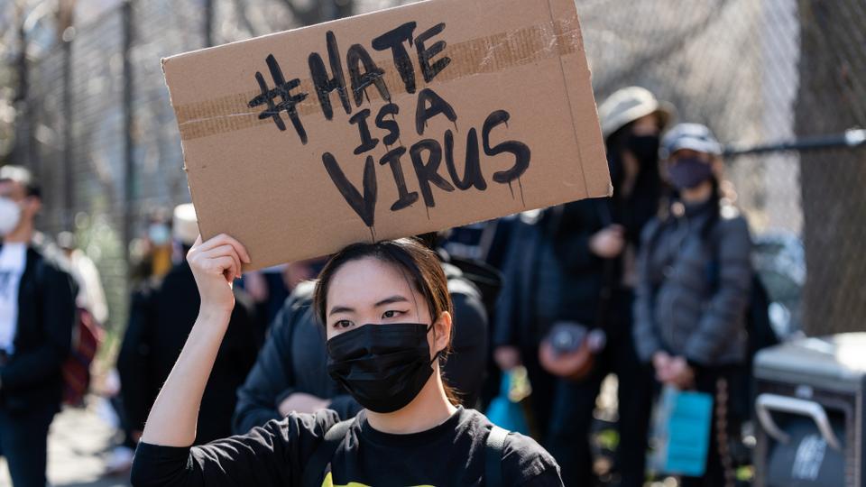 Eunsung Kim rests a sign over her head, while listening to speakers during a Rally Against Hate to end discrimination against Asian-Americans and Pacific Islanders in New York City on March 21, 2021.