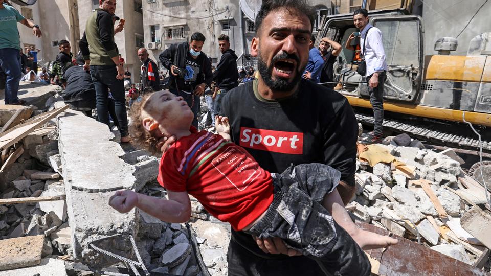 A Palestinian man screams after recovering the body of a child from the rubble of a destroyed building in Rimal residential district in Gaza, on May 16, 2021.