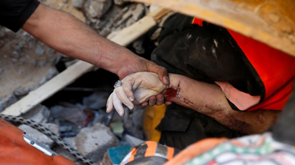 A rescuer holds the hand of a victim at the site of Israeli air strikes, in Gaza, on May 16, 2021.