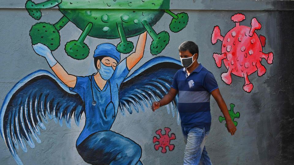 A pedestrian walks past a wall mural representing awareness measures against Covid-19 in Navi Mumbai on June 7, 2021.
