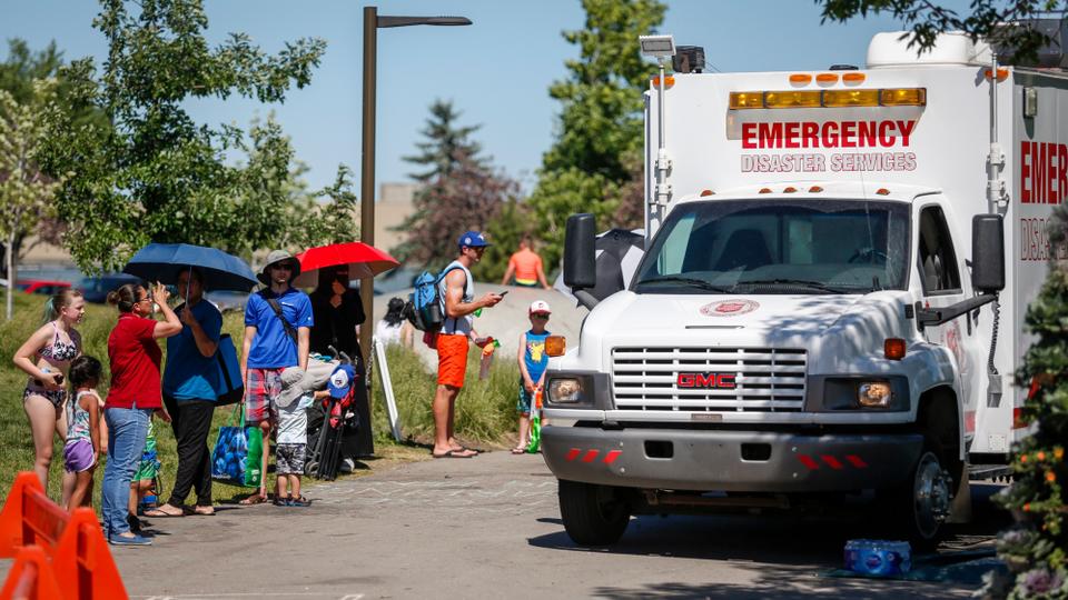 A Salvation Army EMS vehicle is set up as a cooling station as people line up to get into a splash park in Calgary, Alberta on June 30, 2021.