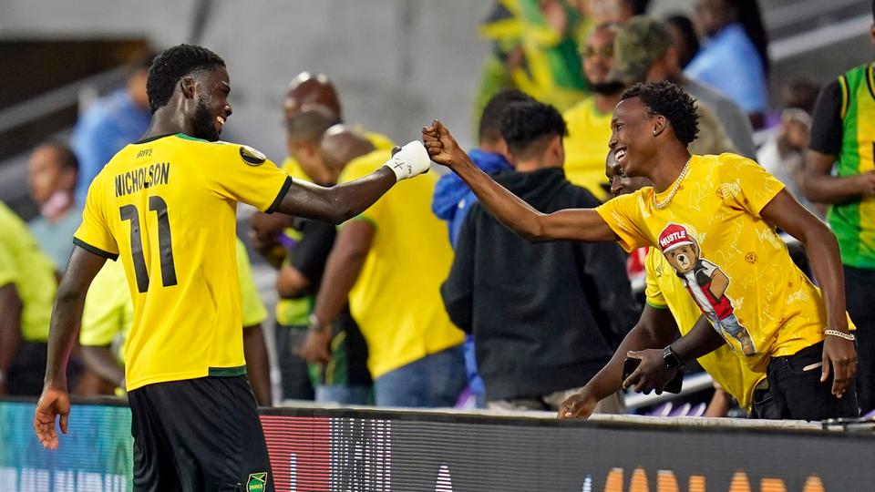 El delantero jamaicano Shamar Nicholson (11) golpea a un fanático mientras celebraba después de vencer a Surinam en un partido de fútbol del Grupo C de la Copa Oro de la CONCACAF el lunes 12 de julio de 2021 en Orlando, Florida.
