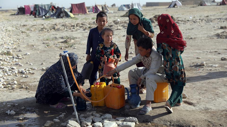 Internally displaced Afghans, who fled their home due to fighting between the Taliban and Afghan security personnel, fill water containers at a camp on the outskirts of Mazar-e-Sharif, northern Afghanistan, on Thursday, July 8, 2021.