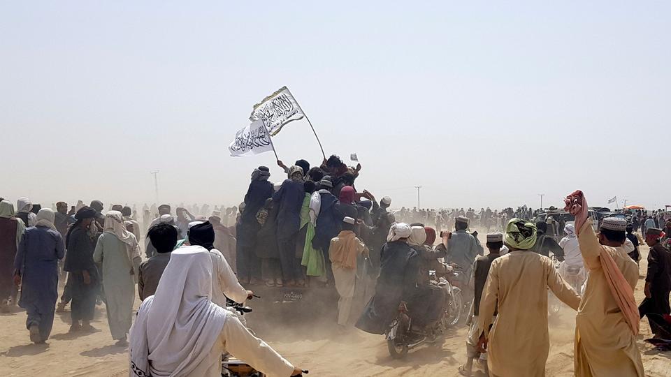 People standing on a vehicle hold Taliban flags as they gather near the Friendship Gate crossing point at the Pakistan-Afghanistan border town of Chaman.