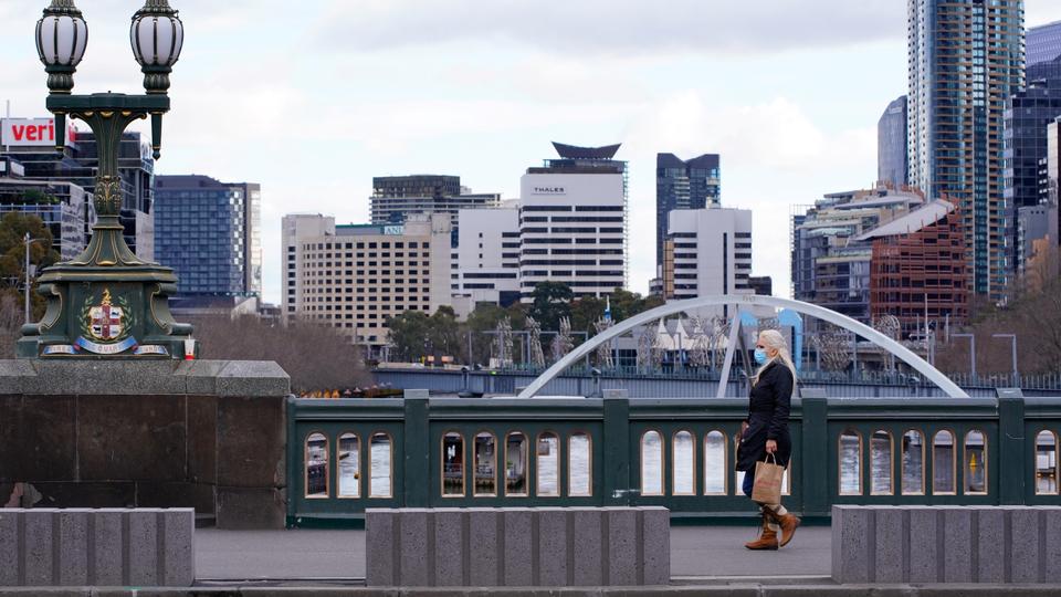 A lone woman, wearing a protective face mask, walks across an unusually quiet city centre bridge on the first day of a lockdown as the state of Victoria looks to curb the spread of a coronavirus disease (COVID-19) outbreak in Melbourne, Australia, July 16, 2021.