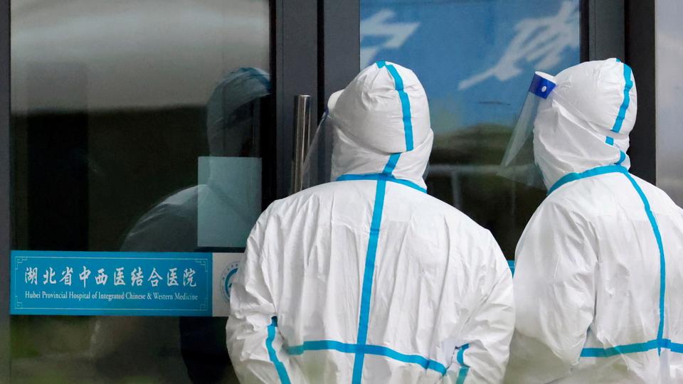 Staff members in protective suits stand at Hubei Provincial Hospital of Integrated Chinese and Western Medicine where members of the World Health Organization (WHO) team tasked with investigating the origins of the coronavirus disease (COVID-19) are visiting, in Wuhan, Hubei province, China January 29, 2021.