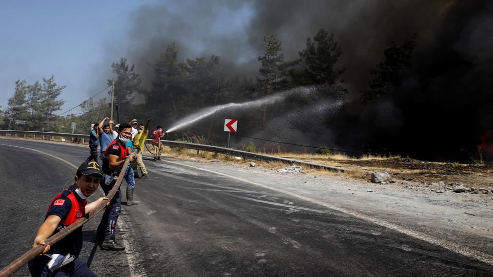 Firefighters and volunteers try to extinguish a wildfire near Marmaris, Turkey
