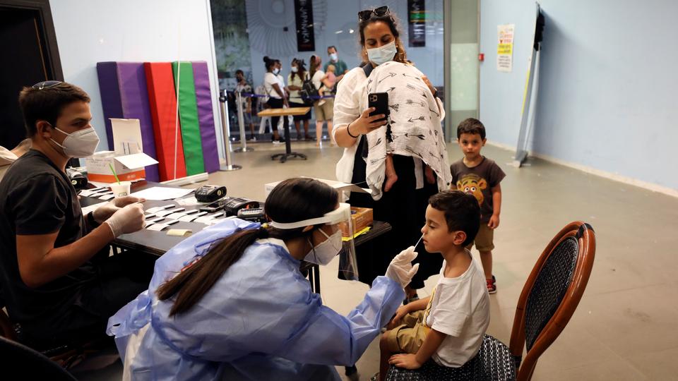 A healthcare worker takes a swab sample from an Israeli child for the coronavirus disease test at a coronavirus testing station in Jerusalem, August 24, 2021.