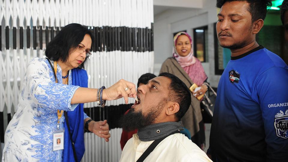 This undated handout photograph released by Philippine's Ramon Magsaysay Foundation on August 31, 2021 shows Bangladeshi scientist Firdausi Qadri (L) administering an oral cholera vaccine to a man in Dhaka.