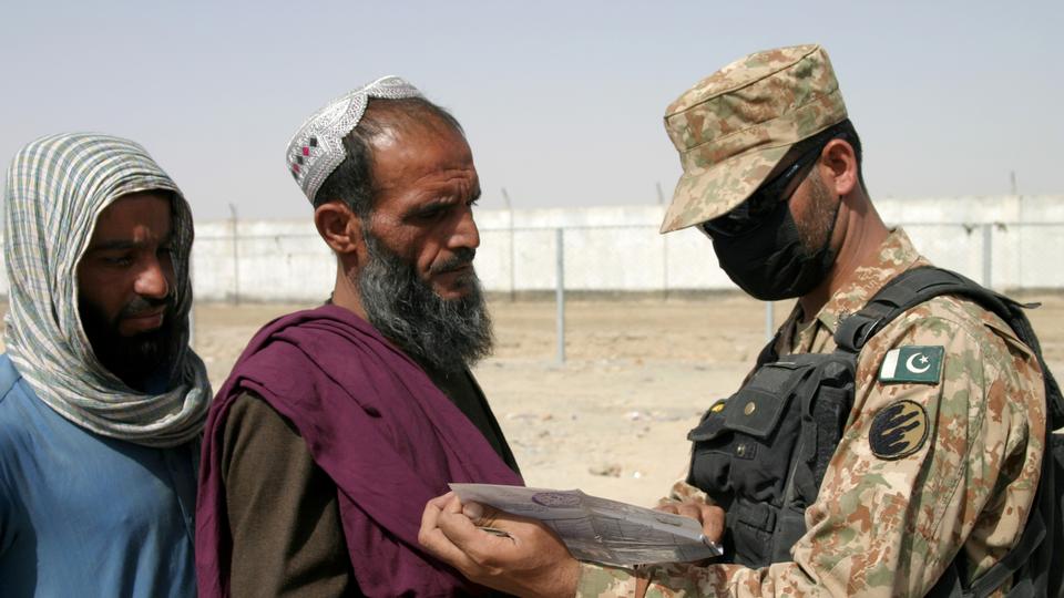 A Pakistani soldier checks documents of people arriving from Afghanistan at the Friendship Gate crossing point in the Pakistan-Afghanistan border town of Chaman, Pakistan August 27, 2021.