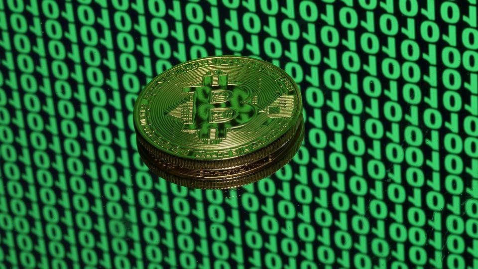 A token of the virtual currency Bitcoin is seen placed on a monitor that displays binary digits in this illustration picture, December 8, 2017.