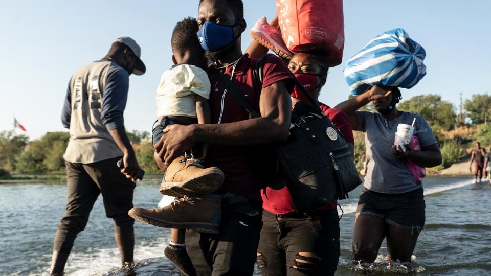 Migrants seeking asylum in the US walk in the Rio Grande river near the International Bridge between Mexico and the US in Ciudad Acuna, Mexico, September 17, 2021.