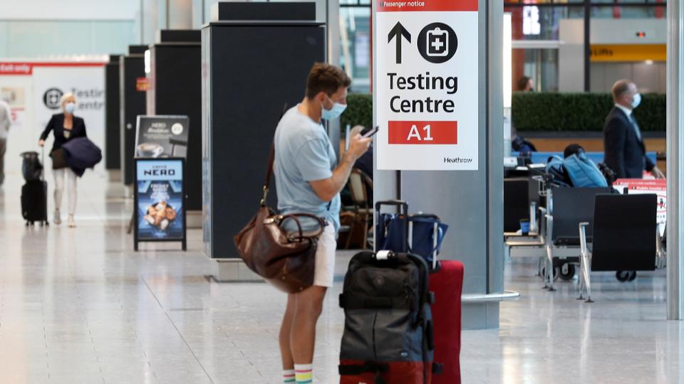 A passenger stands next to a testing centre sign in the International arrivals area of Terminal 5 in London's Heathrow Airport, Britain, August 2, 2021.