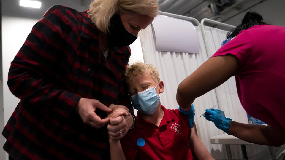 Heather Haworth, left, holds the hand of her 12-year-old son Jeremy as he receives the first dose of the Pfizer vaccine in Santa Ana, California on May 13, 2021.