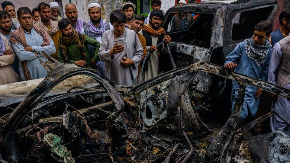 elatives and neighbors of the Ahmadi family gathered around the incinerated husk of a vehicle targeted and hit earlier Sunday afternoon by an American drone strike, in Kabul, Afghanistan, Monday, Aug. 30, 2021.