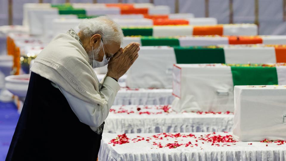 India's PM Narendra Modi pays homage next to the coffin containing the mortal remains of India's Chief of Defence Staff General Bipin Rawat, at an airport in New Delhi on December 9, 2021.