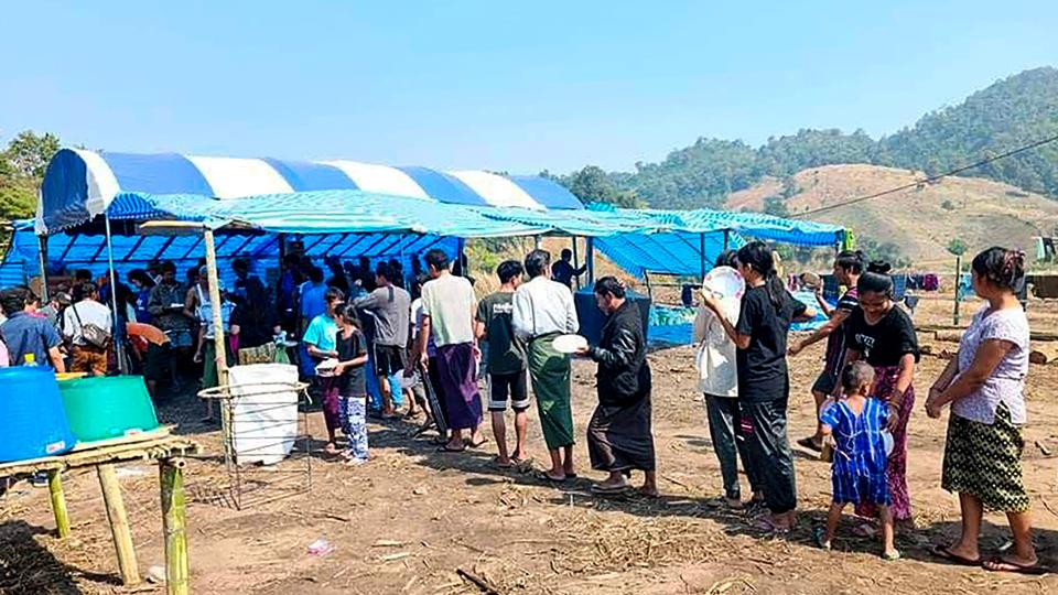 People fleeing due to fighting between the military and the Karen rebels line up to receive food at a temporary lodging for internally displaced people in Karen state on December 25, 2021.