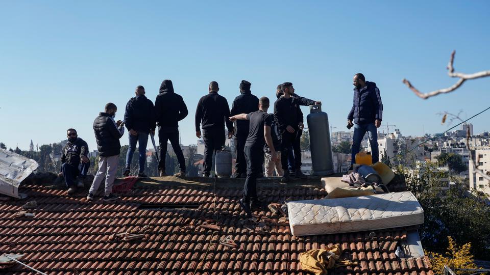 Salhiya family members stand on the roof of their home in Sheikh Jarrah neighborhood with gas canisters in a long standoff against the Israeli police.