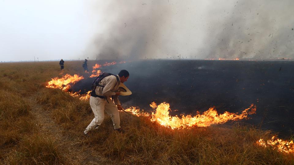 People work to extinguish the fire that continues to consume trees and pastures in San Luis del Palmar, province of Corrientes, Argentina.