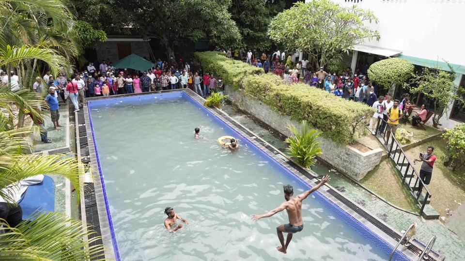 Protesters swim as onlookers wait at a swimming pool in president's official residence a day after it was stormed in Colombo, Sri Lanka.