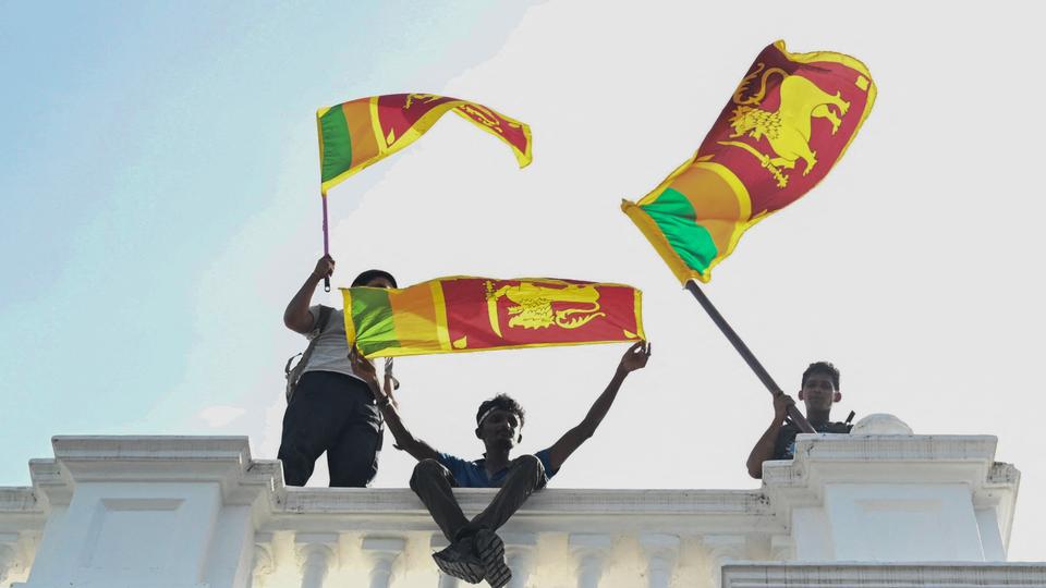 Demonstrators wave Sri Lankan flags from a balcony inside the office building of Sri Lanka's prime minister during an anti-government protest in Colombo.