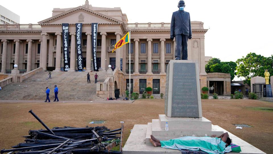 A protester sleeps under a statue in the compound of presidential secretariat in Colombo, Sri Lanka, Friday, July 15, 2022.