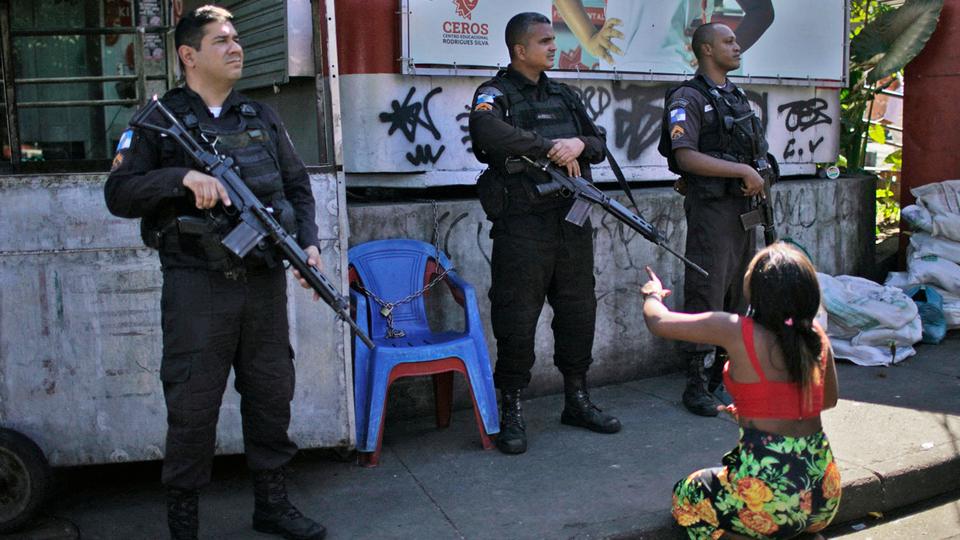 A resident of the Complexo do Alemao favela protests in front of policemen during a police raid in Rio de Janeiro that left more than a dozen dead.