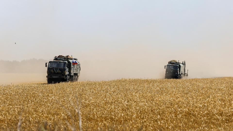 Russian army trucks drive across a wheat field in the course of Ukraine-Russia conflict near the settlement of Olenivka in the Donetsk region.