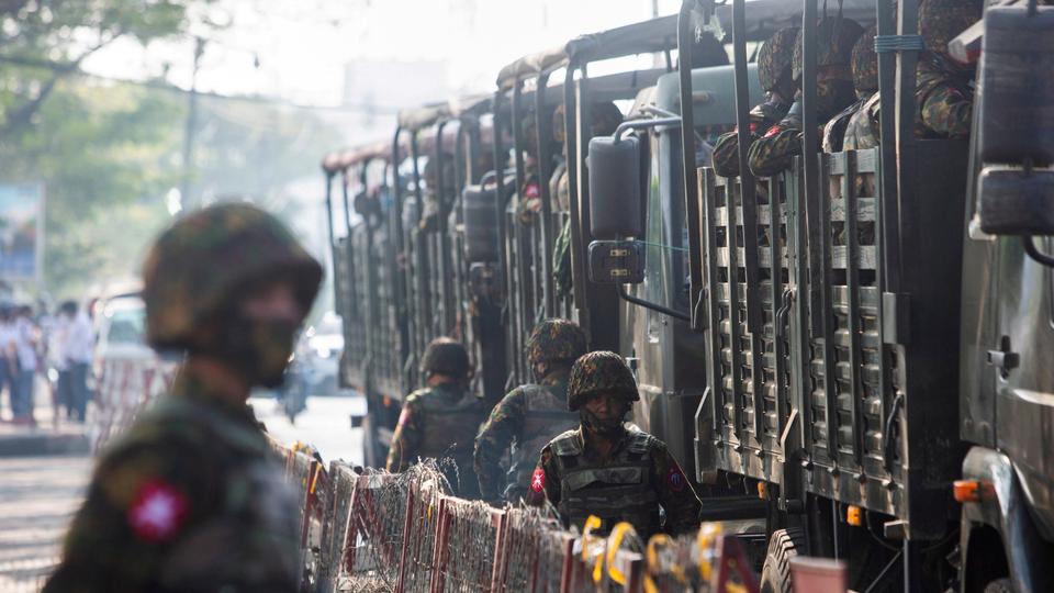 Soldiers stand next to military vehicles as people gather to protest against the military coup, in Yangon, Myanmar, February 15, 2021.