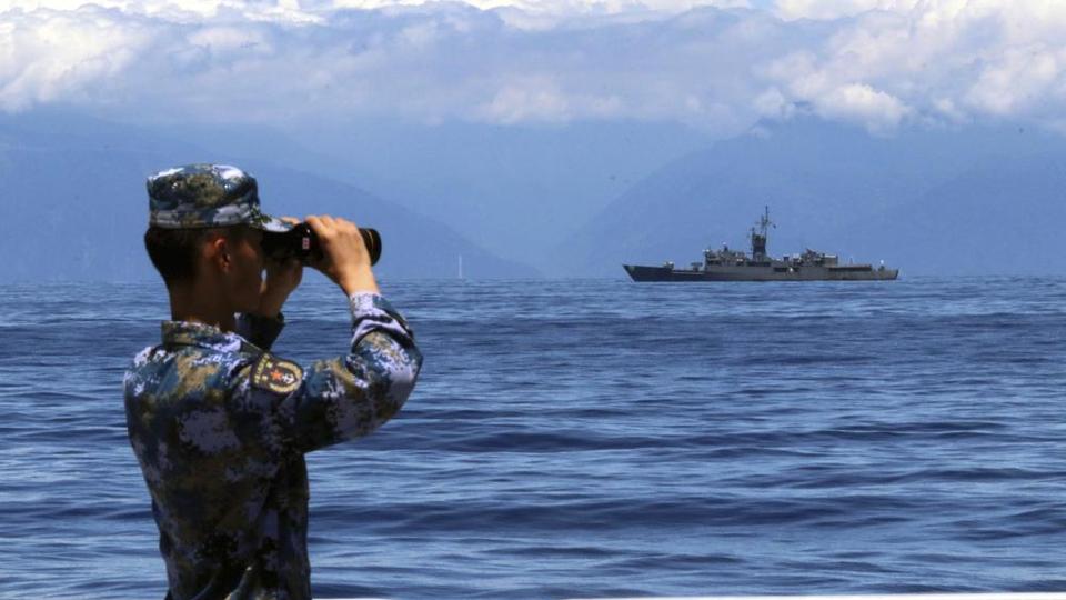 Chinese soldier watches Taiwan's frigate Lan Yang unprecedented Chinese military exercises.