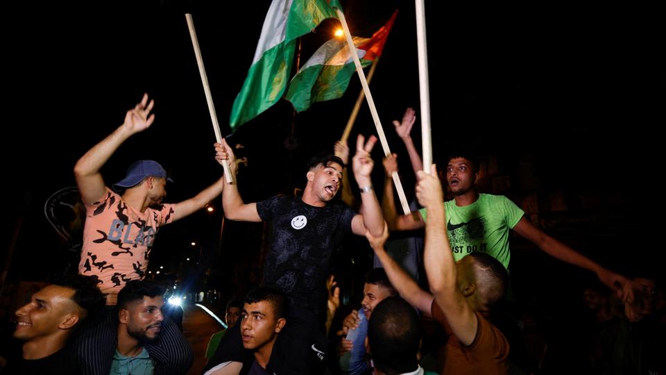 Palestinians celebrate on a street after a ceasefire was announced, in Israel blockaded Gaza August 8, 2022.