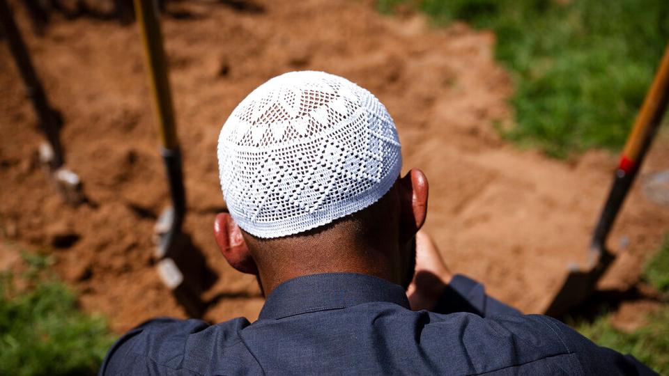 Muslim men pray over the grave of Muhammad Afzaal Hussain, 27, at Fairview Memorial Park in Albuquerque, N.M., on Friday, Aug. 5, 2022.