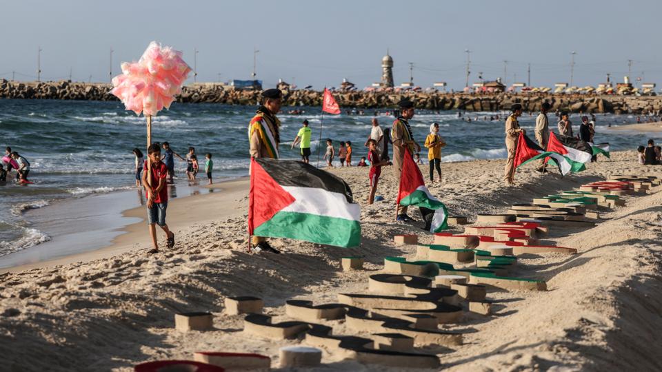 Scouts gather around names carved in the sand of the children who were killed during the recent Israeli aggression on Gaza.