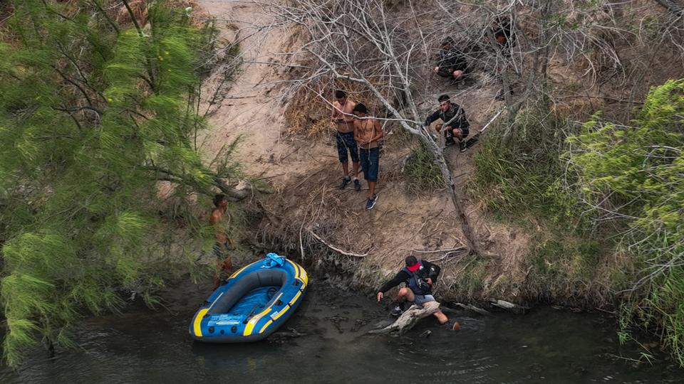 Migrants sit along the river bank after a botched bid by smugglers last month to help them cross Rio Grande river into US from Mexico.