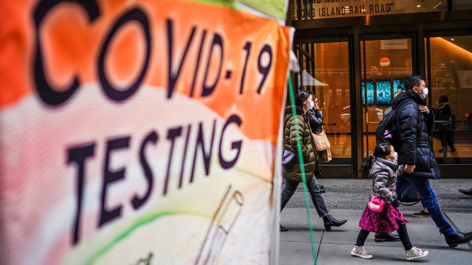 People wearing masks walk next to coronavirus disease Testing site in New York on December 12, 2022.