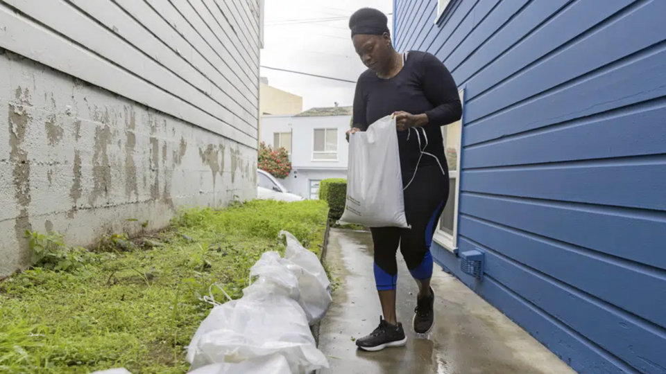 Ifeyinwa Nzerem puts down sandbags in an attempt to prevent flooding from an upcoming storm in San Francisco.