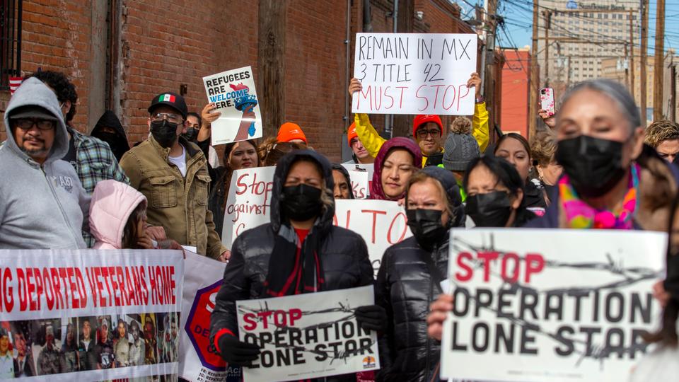 Residents and pro-migrant activists hold signs while marching in downtown El Paso, Texas ahead of Biden's border visit.