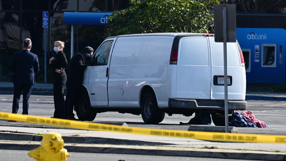 A law enforcement official looks into the window of a van with a body in the driver's seat in Torrance, California, on January 22, 2023.