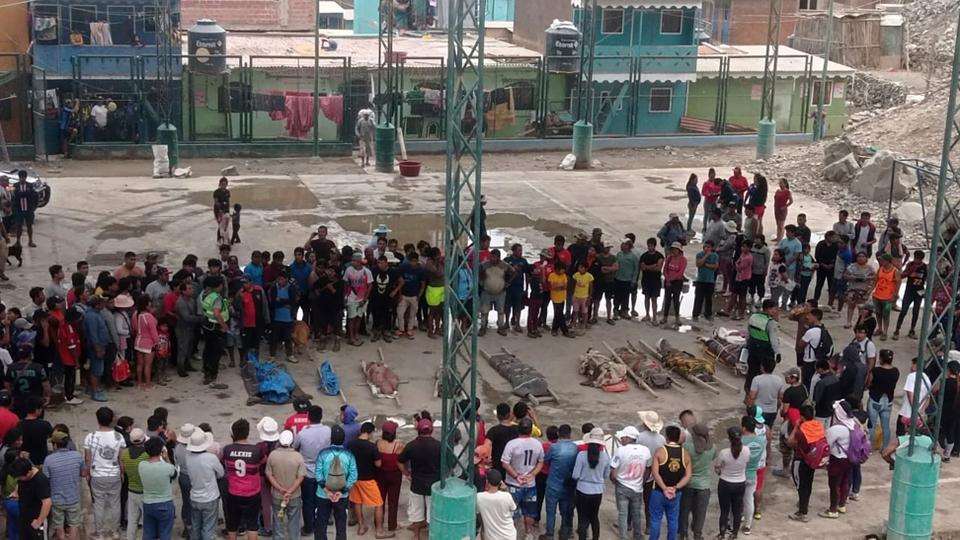 Residents stand around the bodies of victims who perished in the landslides in Camana province.