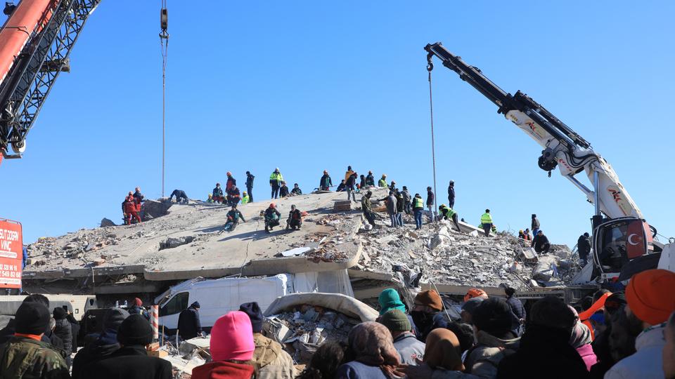 People watch as rescuers and civilians look for survivors under the rubble of collapsed buildings in Nurdagi, in the countryside of Gaziantep.