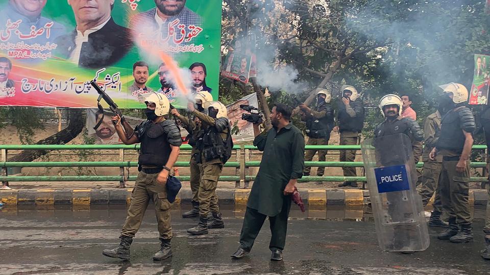 Riot police fire teargas shells to push back supporters of former prime minister Imran Khan gathered outside Khan's house to prevent officers from arresting him, in Lahore on March 14, 2023.