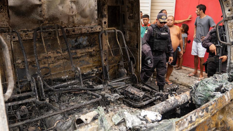 A policeman stands guard next to a burnt commercial truck in Natal, Rio Grande do Norte state.