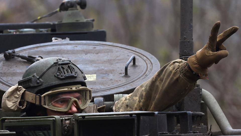 A Ukrainian serviceman flashes a victory sign as he drives towards the frontline during heavy fighting at the frontline of Bakhmut and Chasiv Yar, in Chasiv Yar.