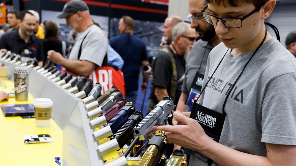 A young man tries out a gun at the National Rifle Association's annual convention in Indianapolis.