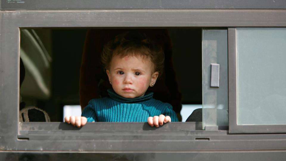 A girl looks out of a bus carrying rebels and their families as they wait to be evacuated, at Harasta highway outside Jobar, in Damascus, Syria on March 25, 2018.